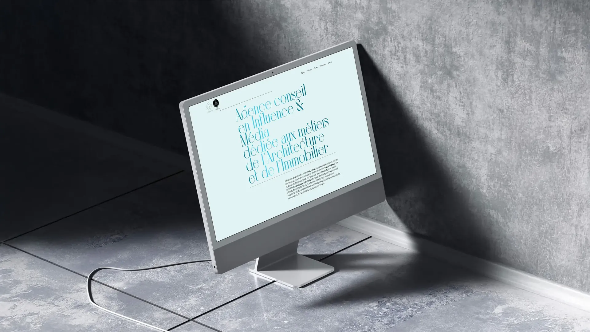 Site de l'Agence Première sur un écran d'ordinateur, dans un décor de béton